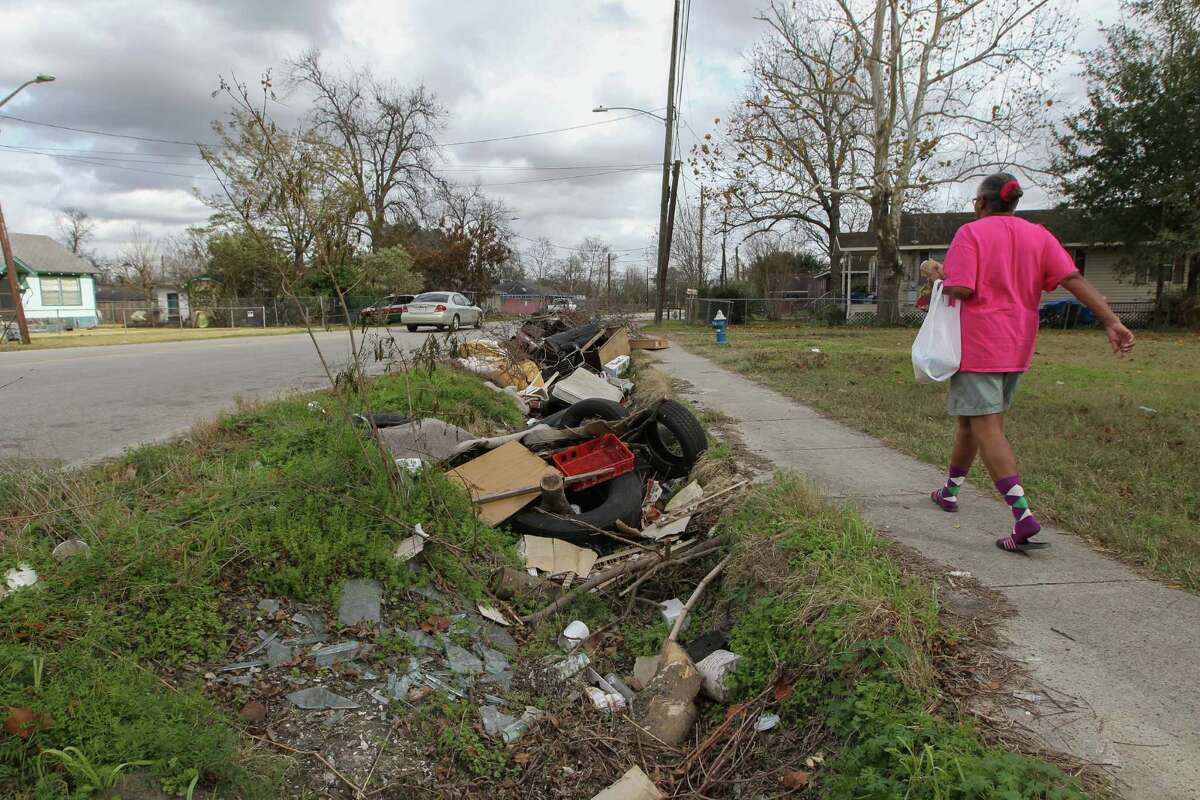 A woman walks passed a mound of ditch debris in Houston near Collingsworth Street and Lockwood Drive on Tuesday. Mayor Sylvester Turner is seeking $10 million towards small emergency drainage repair. Ditches full of debris can cause drainage issue.