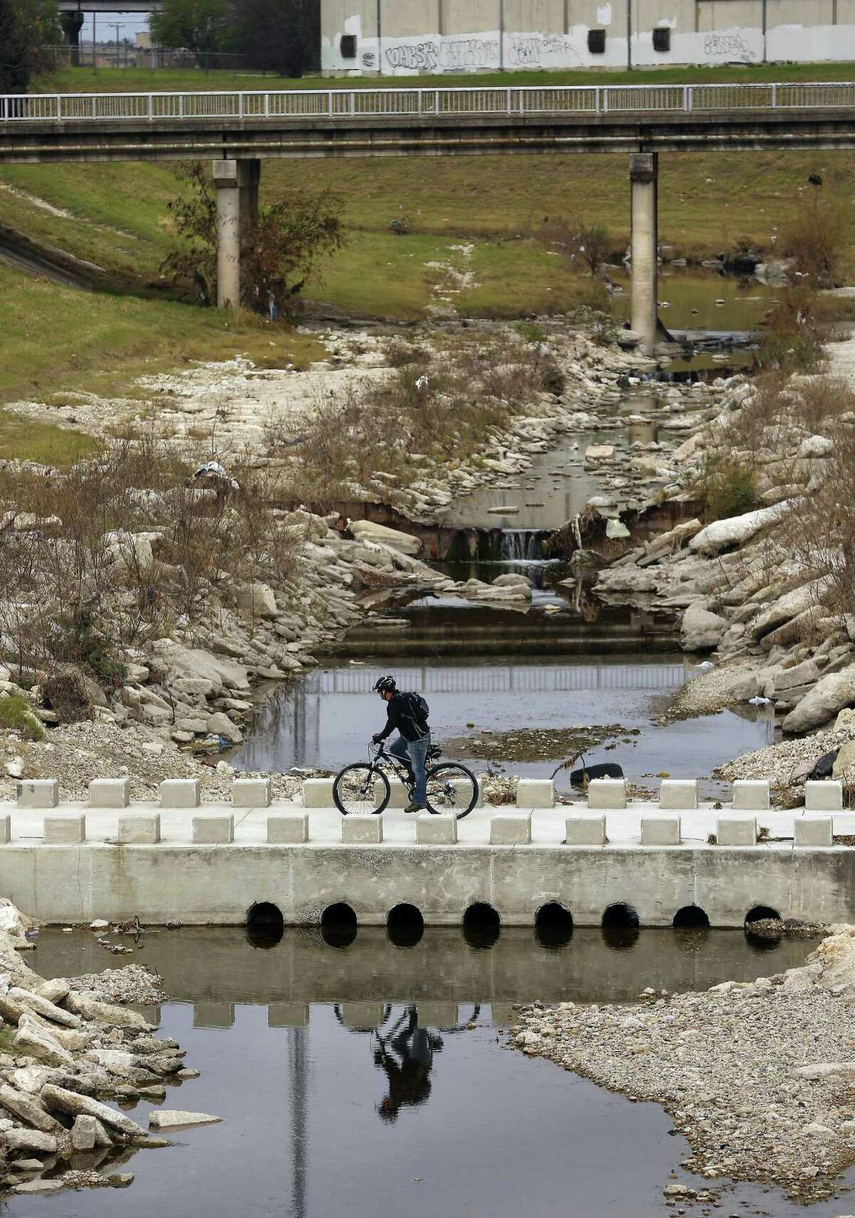 A bicyclist crosses Alazan Creek on Jan. 5 on the Apache Creek Trailway just upstream from the intersection of the two waterways.