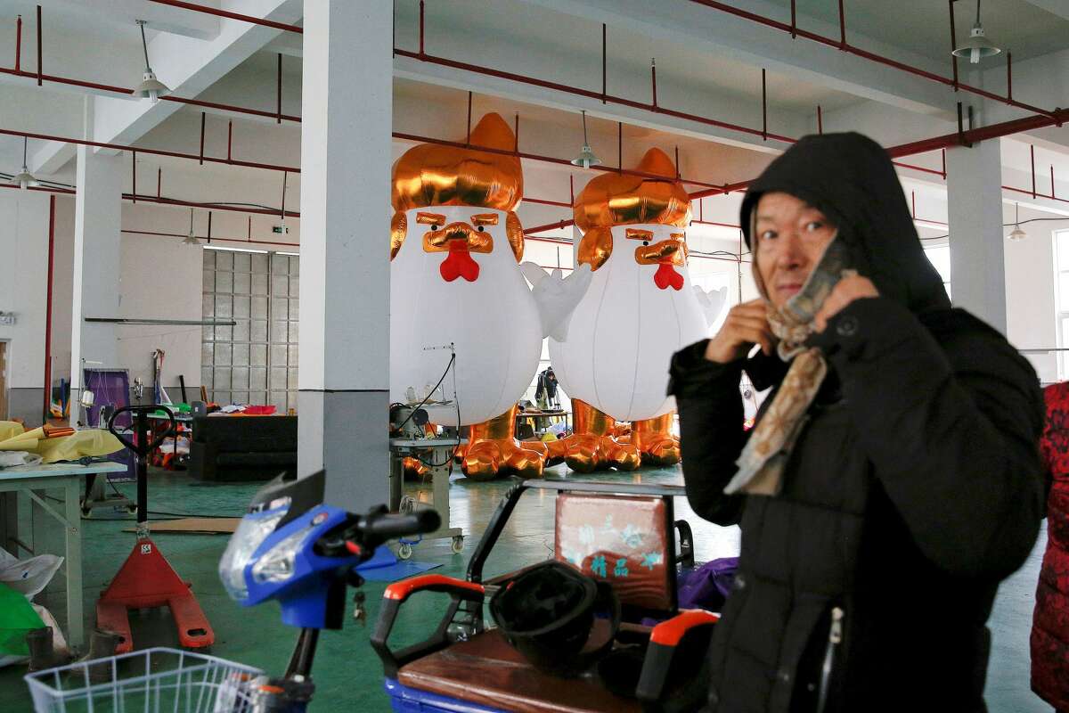 A visitor is seen in front of inflatable chickens that local media say bear resemblance to President-elect Donald Trump at a factory ahead of the Year of the Rooster in Jiaxing, Zhejiang province, China.
