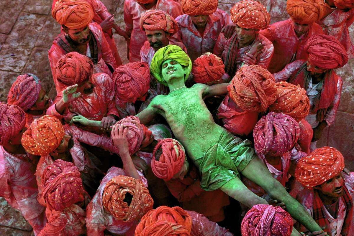 “Rajathan/1996” captures a crowd carrying a man during the Holi festival.