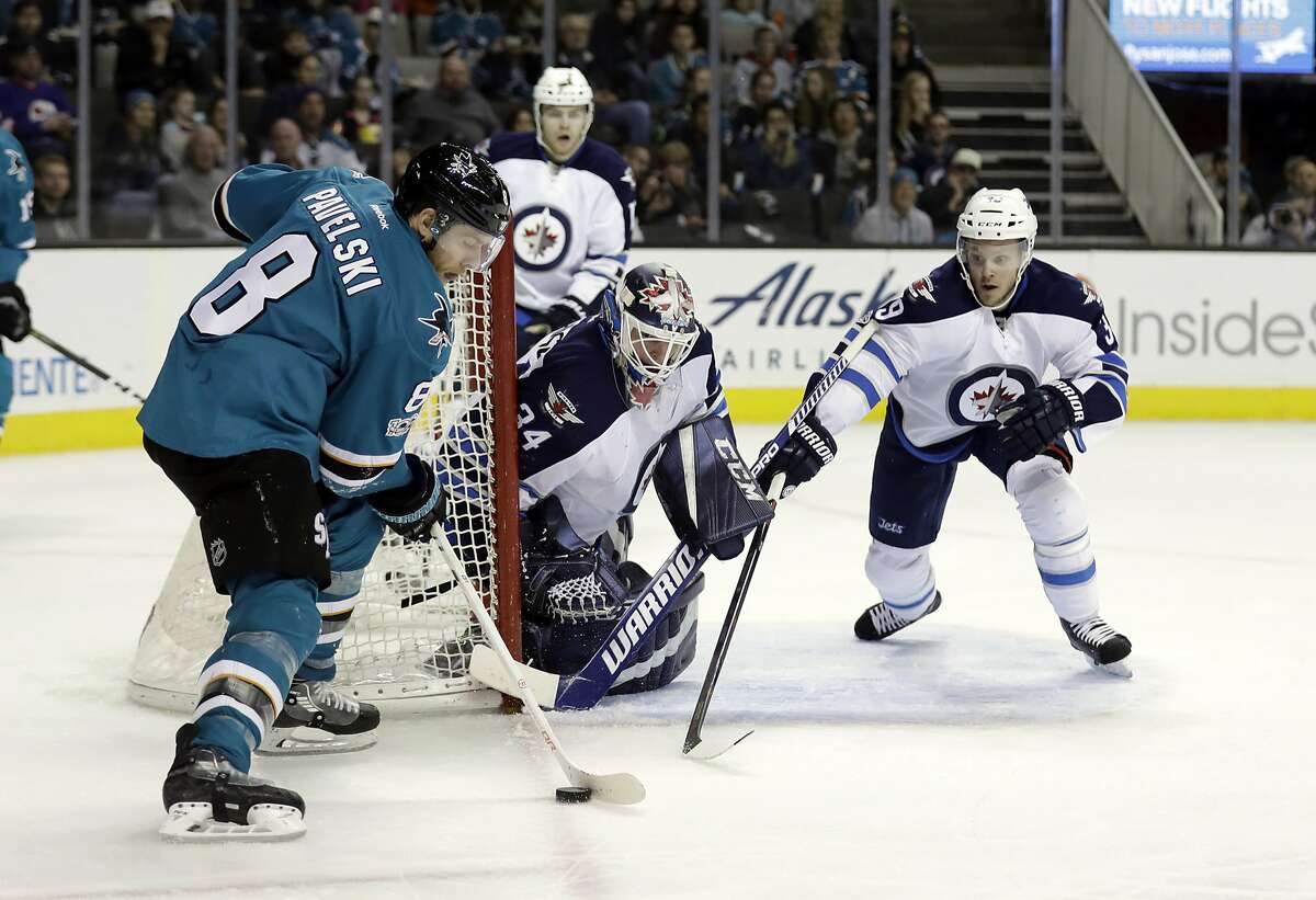 San Jose Sharks' Joe Pavelski (8) controls the puck in front of Winnipeg Jets goalie Michael Hutchinson (34) and Toby Enstrom, right, during the second period of an NHL hockey game, Monday, Jan. 16, 2017, in San Jose, Calif. (AP Photo/Marcio Jose Sanchez)