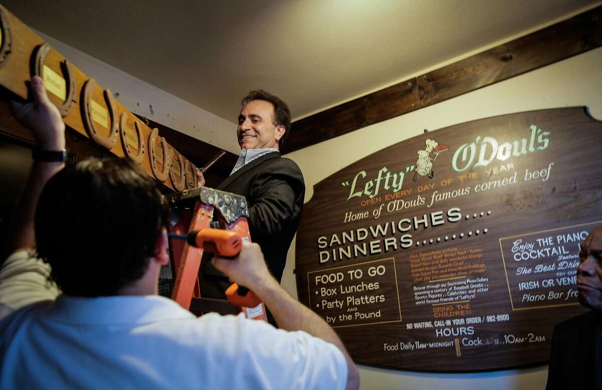 Owner Nick Bovis takes down memorabilia from the exterior of his restaurant to move to its new location, after speaking at a press conference regarding the closing of his restaurant Lefty O'Doul's in San Francisco, Calif., on Monday, Jan. 16, 2017.