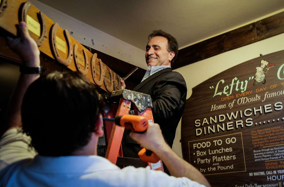 Owner Nick Bovis takes down a plaque from the exterior of his restaurant to move to its new location, after speaking at a press conference regarding the closing of his restaurant Lefty O'Doul's in San Francisco, Calif., on Monday, Jan. 16, 2017.