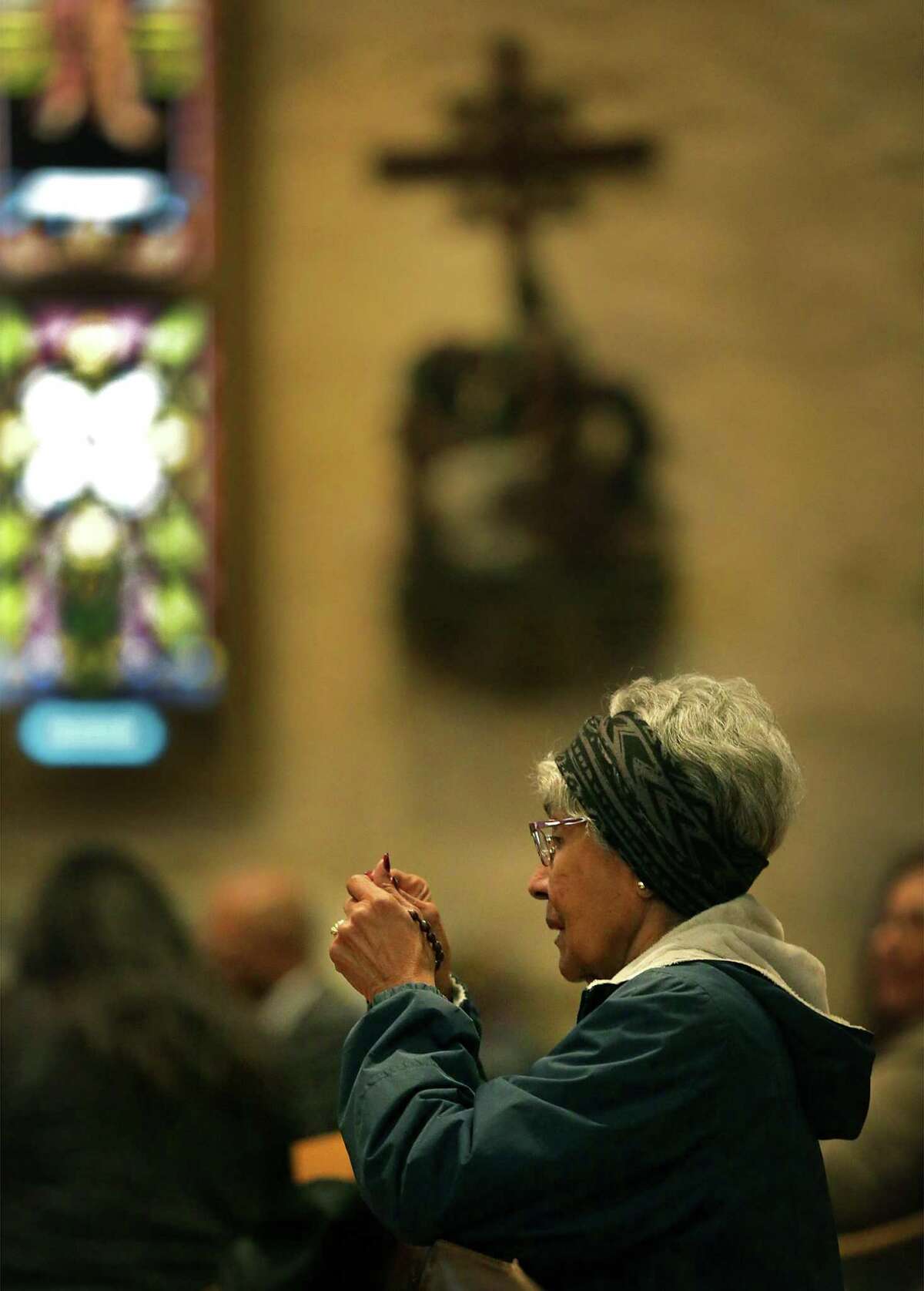 A worshiper prays with her rosary during Archbishop Emeritus Patrick Flores's funeral at San Fernando Cathedral on Tuesday, Jan. 17, 2017.