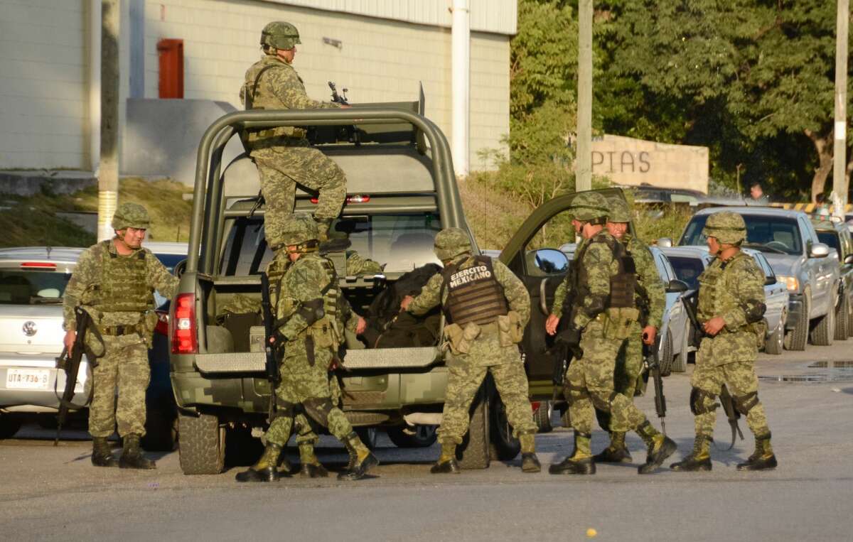 Mexican soldiers arrive at the place where a shooting erupted after an attack against the building of the Quintana Roo State Prosecution, in Cancun, Mexico, on January 17, 2017. The shooting happened as Mexican authorities investigate whether a feud over local drug sales was behind a nightclub shooting that killed three foreigners and two Mexicans Monday at the Blue Parrot club during the BPM electronic music festival in Playa del Carmen, a usually peaceful Caribbean seaside town. / AFP / STR