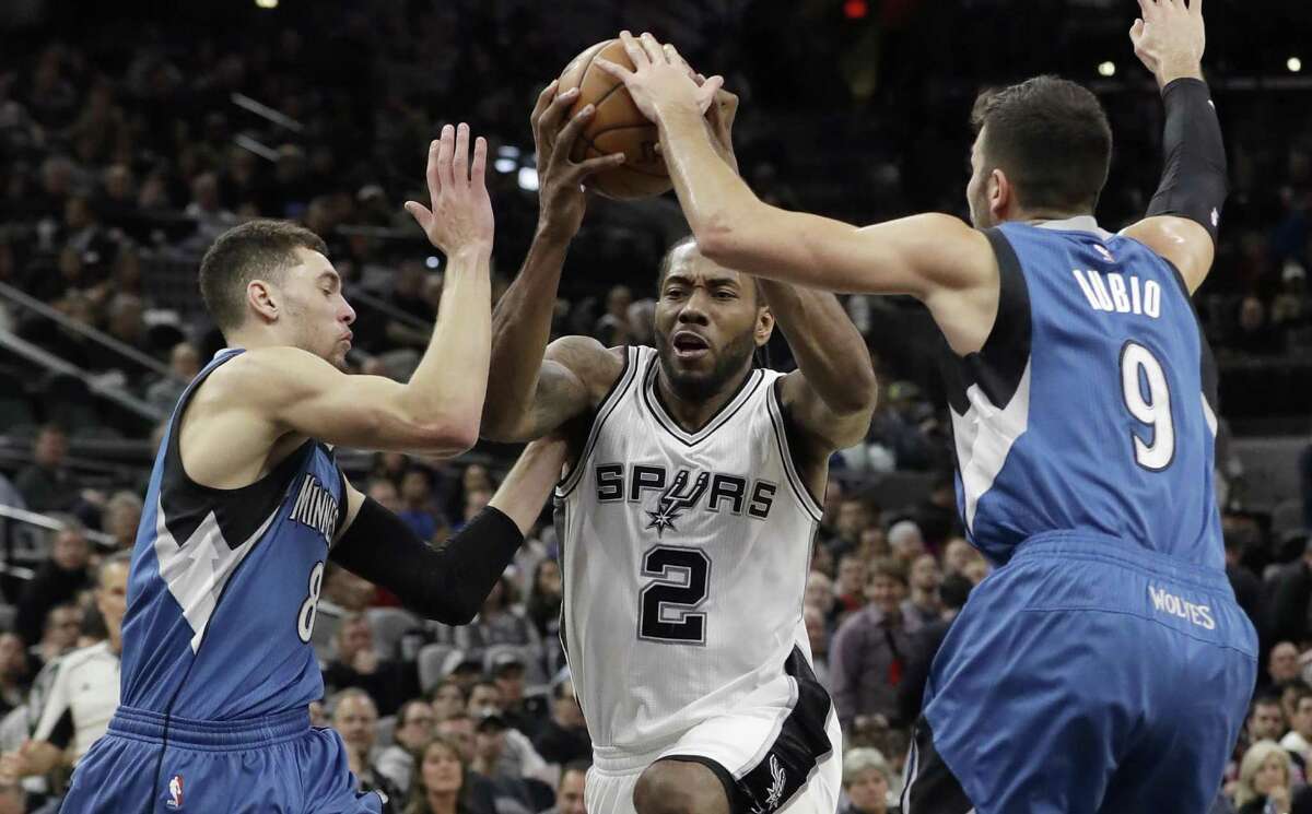 Spurs forward Kawhi Leonard drives to the basket between Minnesota Timberwolves defenders Zach LaVine (8) and Ricky Rubio (9) during the second half on Jan. 17, 2017, in San Antonio. The Spurs won 122-114.