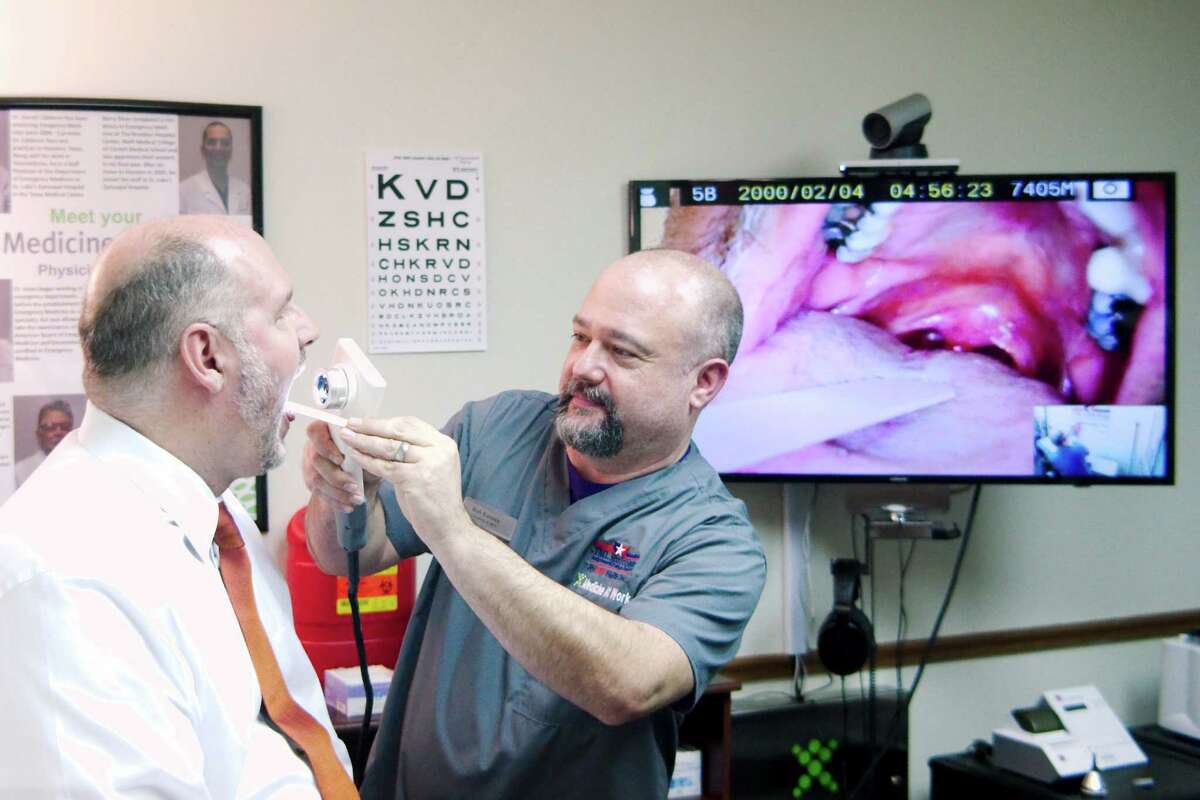 Paramedic Rob Koonce performs a throat examination on Nu Physicia CEO Dr. Glenn Hammock during a demonstration of telemedicine technology Thursday, Jan. 12.