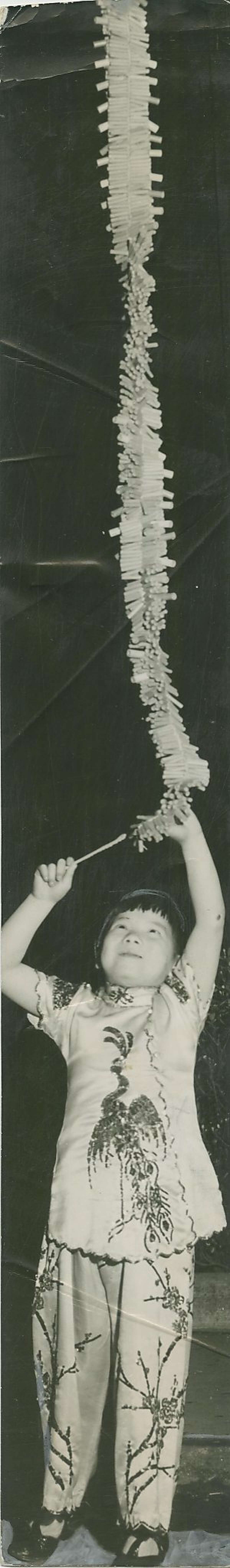 孩子点亮了一长串鞭炮在唐人街饭碗游行和拍卖,1940年2月10日