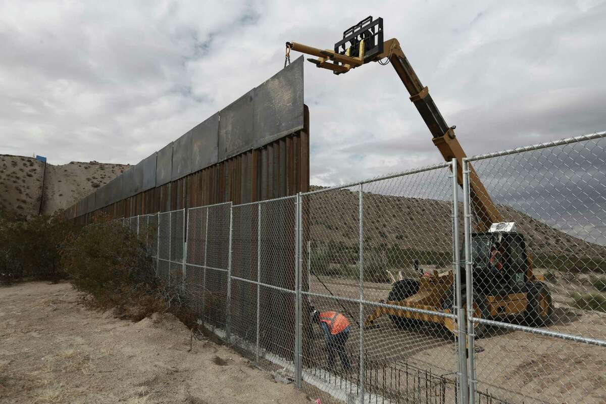 FILE - In this Nov. 10, 2016 file photo, workers raise a taller fence along the Mexico-US border between the towns of Anapra, Mexico and Sunland Park, New Mexico, where for almost two decades a Mass has been celebrated on Day of the Dead to remember migrants who have died trying to cross the fence. President-elect Donald Trump has threatened to force Mexico to pay for a wall along the nearly 2,000-mile (3,145-kilometer) border. (AP Photo/Christian Torres, File)