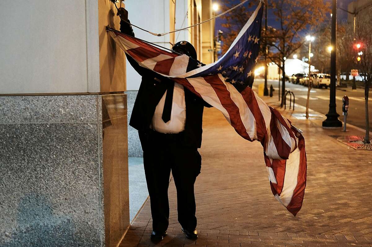 A building security guard raises the American Flag on the morning of the inauguration on January 20, 2017 in Washington, DC. Washington and the entire nation are preparing for the transfer of the United States presidency later today as Donald Trump is sworn is as the 45th president Friday. (Photo by Spencer Platt/Getty Images)
