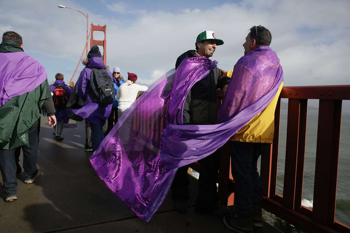 James Bosch (l to r) and John Rowe, both of San Francisco, wear purple capes as they stand on the Golden Gate Bridge with others before Bridge Together on Friday, January 20, 2017 in San Francisco, California.