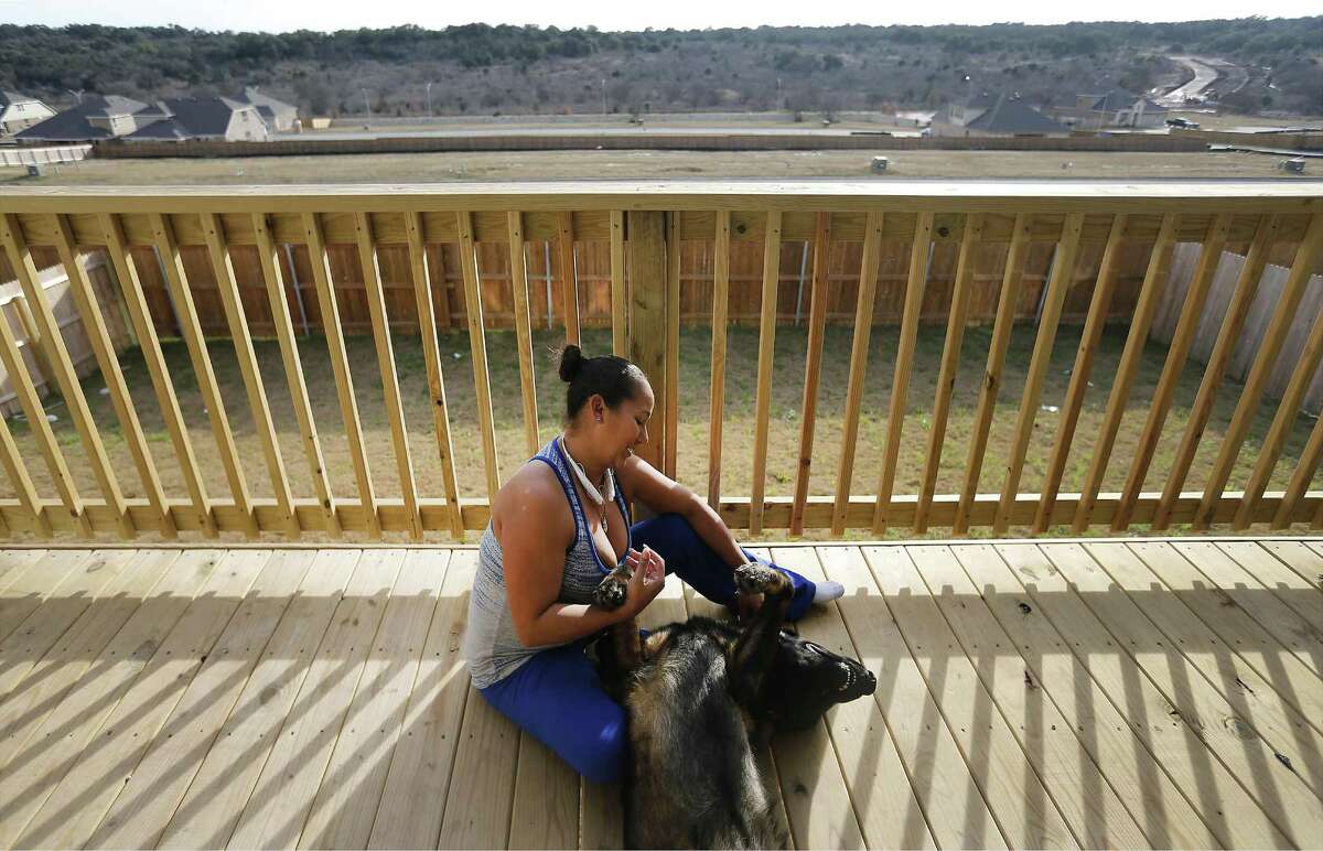 Maritza Arroyo plays with her German shepherd on her balcony overlooking the Ladera master-planned community.