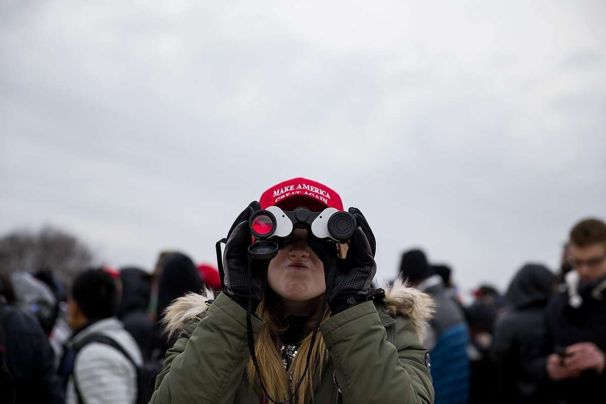 An attendee looks through binoculars at the National Mall during the 58th presidential inauguration in Washington, D.C., U.S., on Friday, Jan. 20, 2017. Donald Trump will become the 45th president of the United States today, in a celebration of American unity for a country that is anything but unified. Photographer: Eric Thayer/Bloomberg