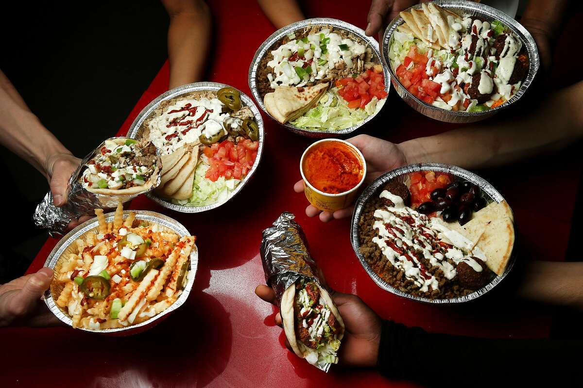 Platters, sandwiches and side orders are seen at The Halal Guys located at 340 O'Farrell St., on Thursday, Jan. 19, 2017 in San Francisco, Calif. Clockwise: Combo platter; gyro and falafel combo platter; gyro platter; falafel sandwich; a side of fries; chicken sandwich; and chicken platter are seen.