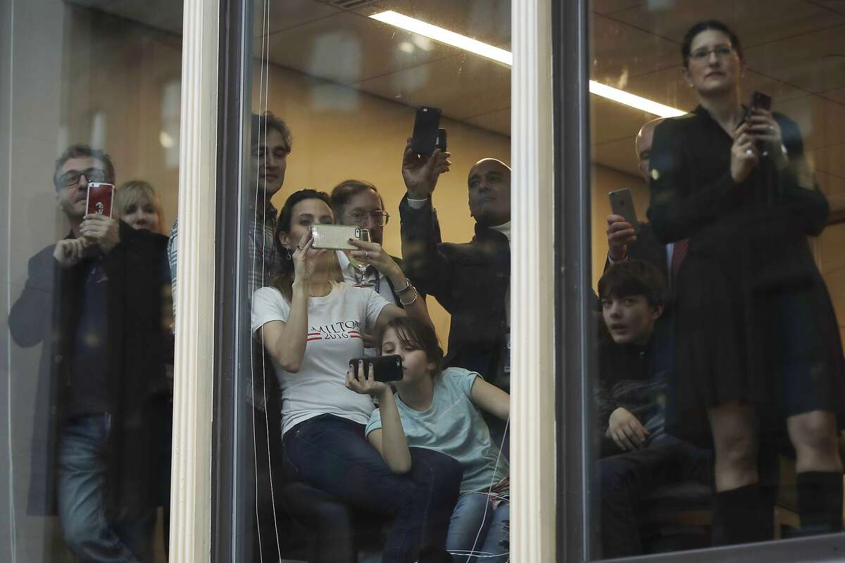 People take photos as President Donald Trump passes by during the inauguration parade in Washington, Friday, Jan. 20, 2017.