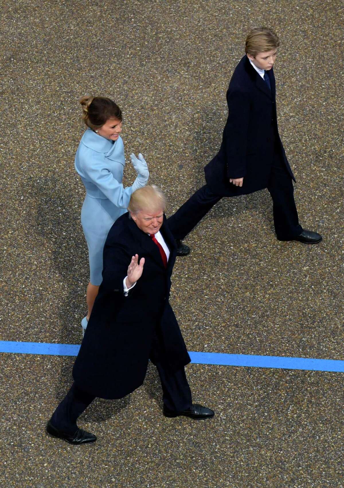 President Donald Trump waves as he walks with first lady Melania Trump and their son Barron during the 58th Presidential Inauguration parade for President Donald Trump in Washington. Friday, Jan. 20, 2017. (AP Photo/Susan Walsh)
