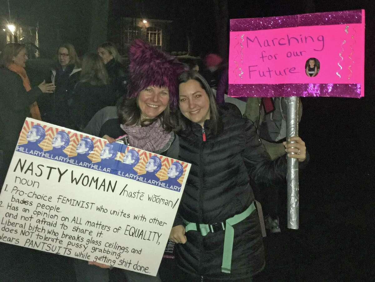 Colleen Morris, left, and Samantha Casella, right, of Darien, hold signs outside Second Congregational Church in Greenwich at 3:30 a.m. on Saturday, Jan. 21, 2017.