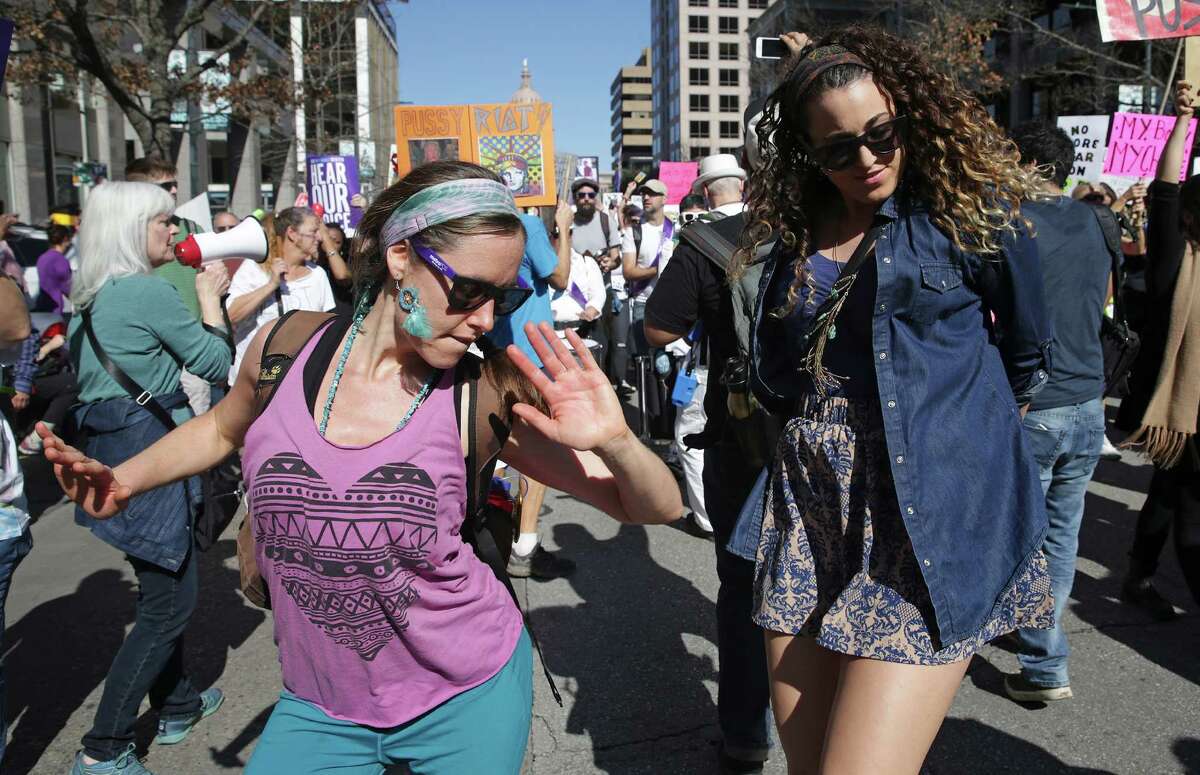 Alice Seitzer (left) and Angela Guilfoyle dance to drum beat as demonstators march on Congress Avenue in Austin during the Women's March on Austin on January, 21, 2017.