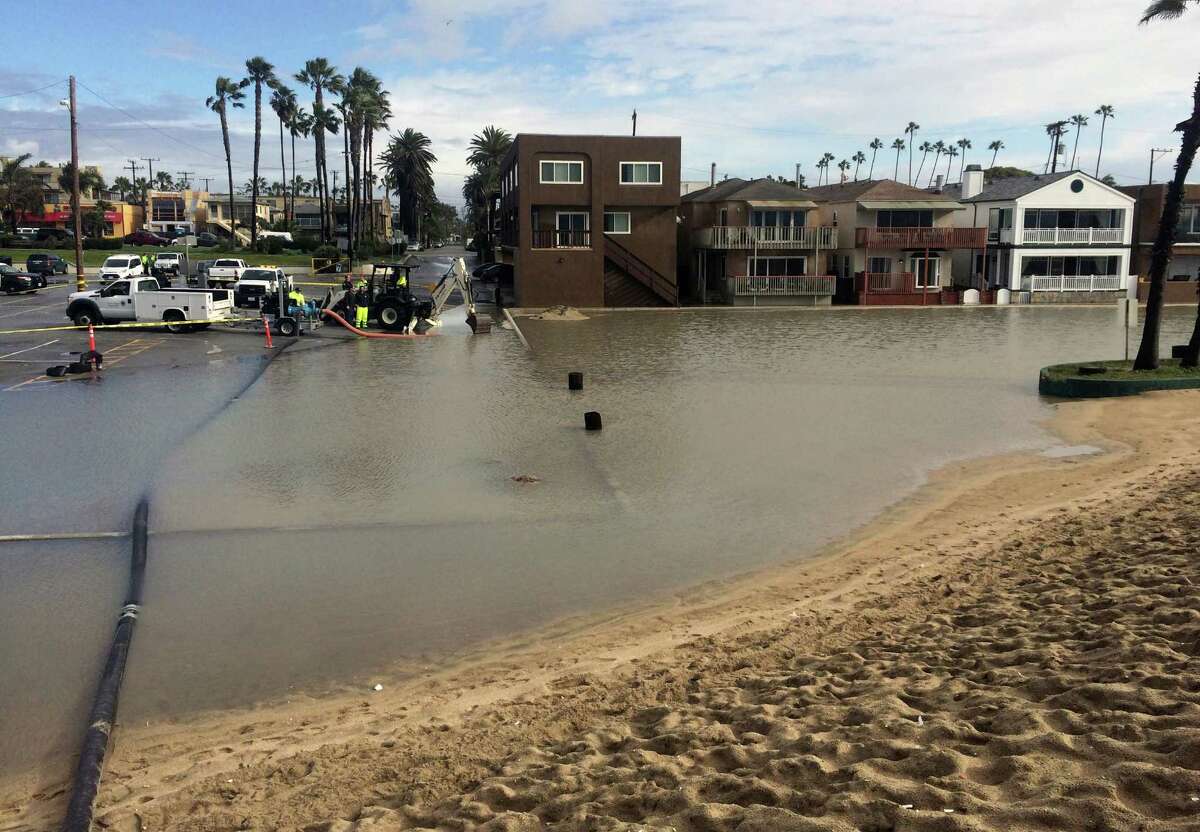 Floodwater is pumped out over a sand berm and toward the ocean in Seal Beach, Calif., on Monday, Jan. 23, 2017. The tail end of a punishing winter storm system lashed California with thunderstorms and severe winds Monday after breaking rainfall records, washing out roads and whipping up enormous waves. (AP Photo/Amy Taxin)