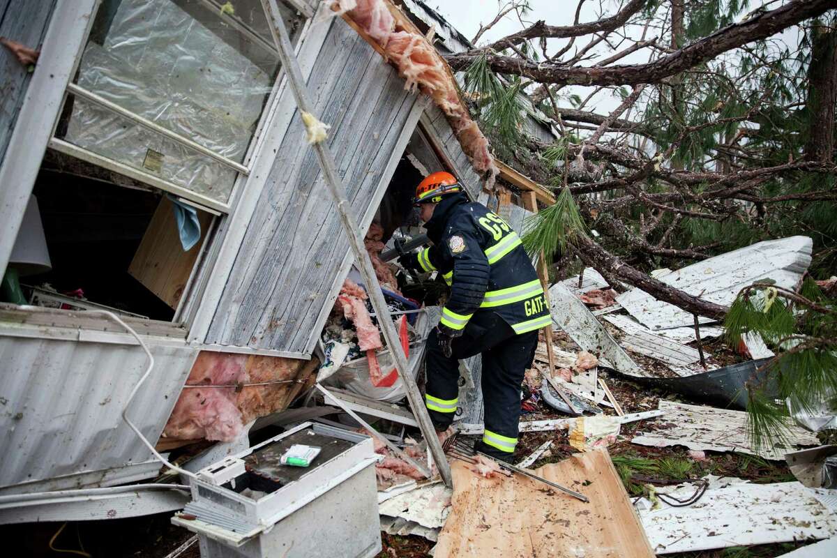 A rescue worker enters a hole in the back of a mobile home Monday, Jan. 23, 2017, in Big Pine Estates that was damaged by a tornado, in Albany, Ga. Fire and rescue crews were searching through the debris, looking for people who might have become trapped when the deadly storm came through. (AP Photo/Branden Camp)