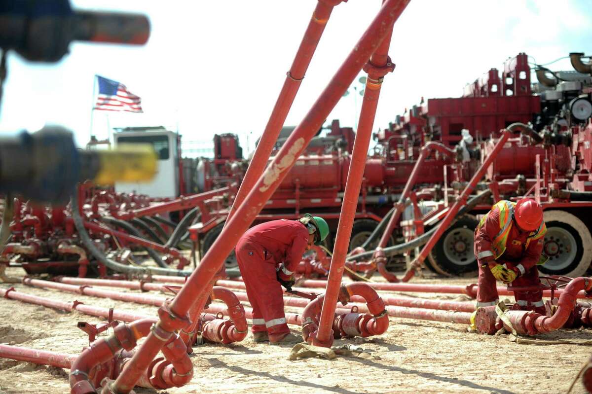 Halliburton employees work on high-pressure pipes supplying a hydraulic fracturing site managed by Octane Energy ﻿near Stanton in West Texas. ﻿