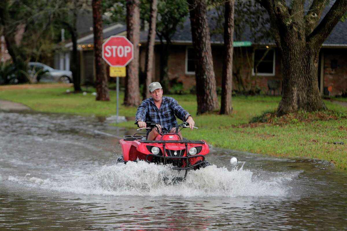 Mark Taylor crosses N. Braeswood Blvd. at Braewick on a four-wheeler past several flooded vehicles, Tuesday, Jan. 17, 2017, in Houston. Taylor's house around the corner just north of Brays Bayou has flooded in the two previous significant floods, but no water entered his house this time. ( Mark Mulligan / Houston Chronicle )