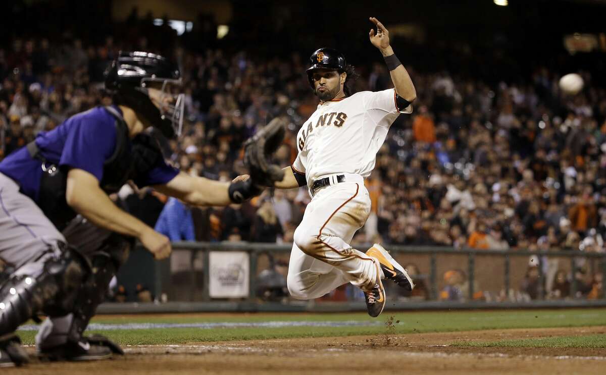 San Francisco Giants' Angel Pagan, right, scores past Colorado Rockies catcher Nick Hundley on a sacrifice fly by Matt Duffy during the eighth inning of a baseball game on Tuesday, April 14, 2015, in San Francisco. (AP Photo/Marcio Jose Sanchez)