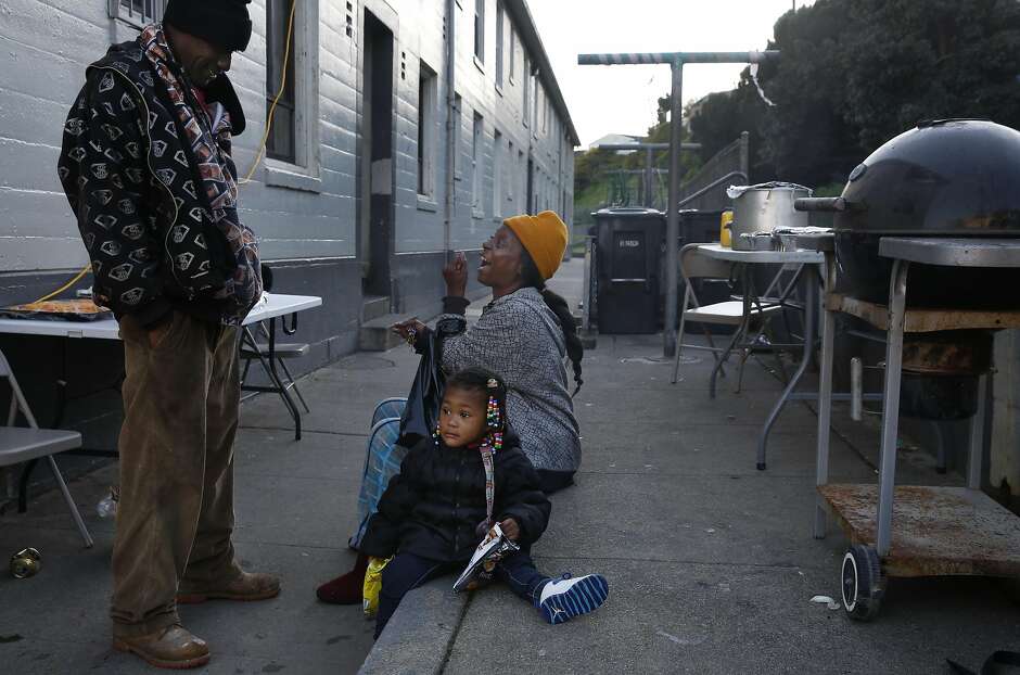 Longtime residents Curtis Cosby (left) and Lisa M. Washington chat while Washington's granddaughter Alanna, 1, sits nearby during a birthday barbecue for Cosby’s daughter in the Potrero Terrace and Annex public housing complex.