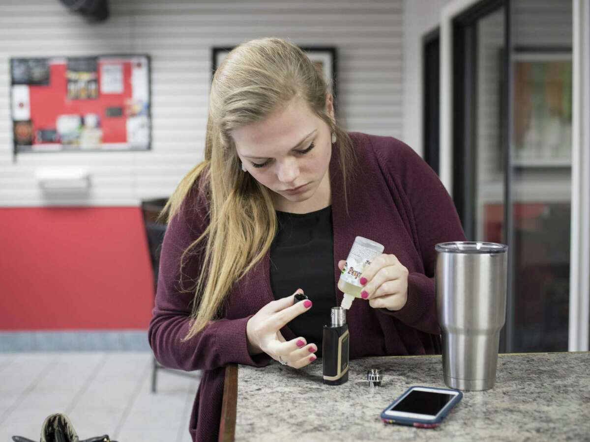 Shellbey Knight refills her e-cigarette with e-juice at the Texas Vape Store off of Austin Highway on Jan. 23 in San Antonio. A bill with bipartisan support in the Texas Legislature would raise the age at which one can buy tobacco products and e-cigarettes from 18 to 21 years old.