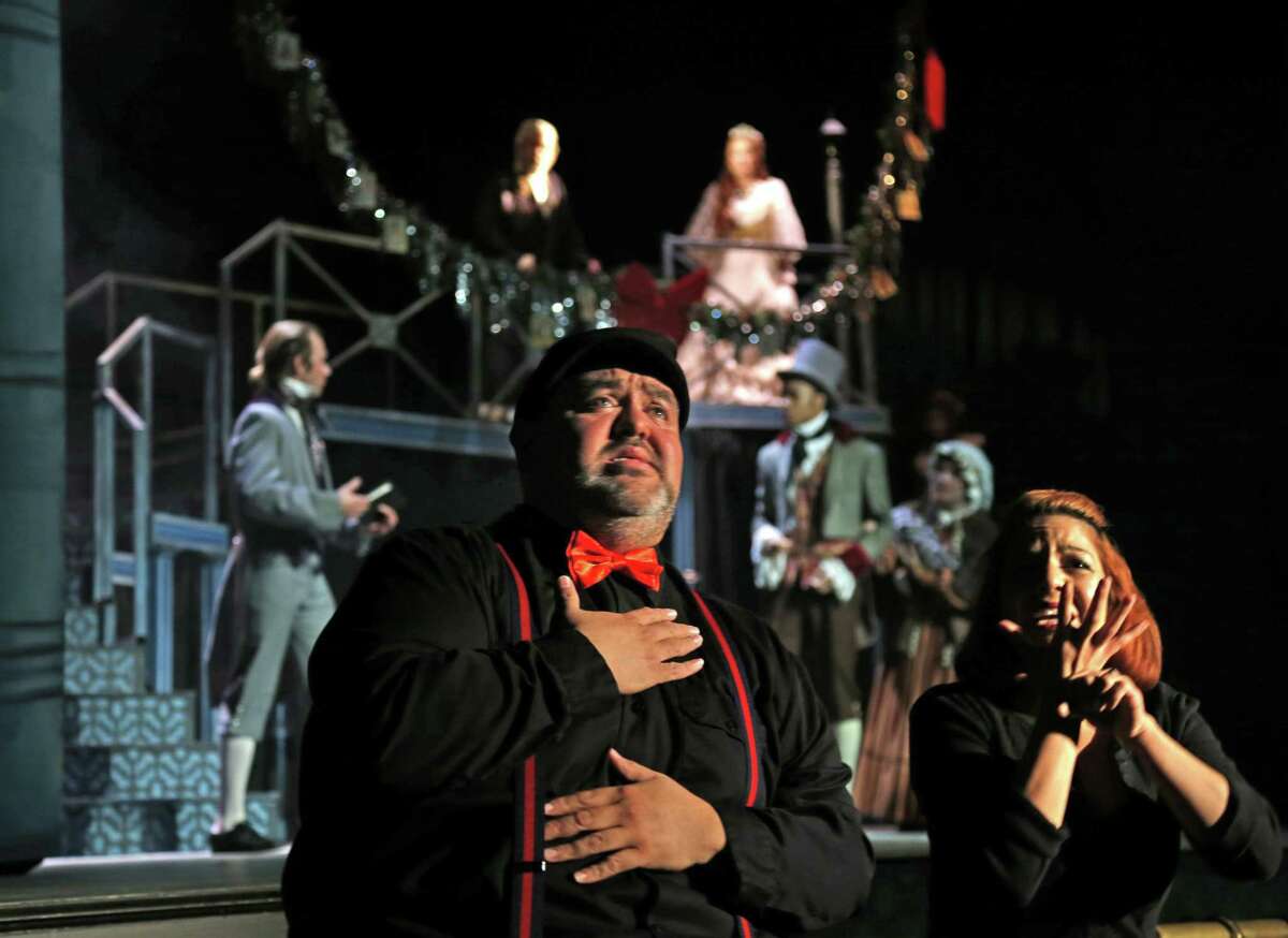 Robert Cardoza and Claudia Flores sign near the stage during a 2015 performance of “A Christmas Carol” at The Playhouse San Antonio. Cardoza, working with a roster of interpreters, has signed one performance of every production on the theater’s Russell Hill Rogers stage ever since.