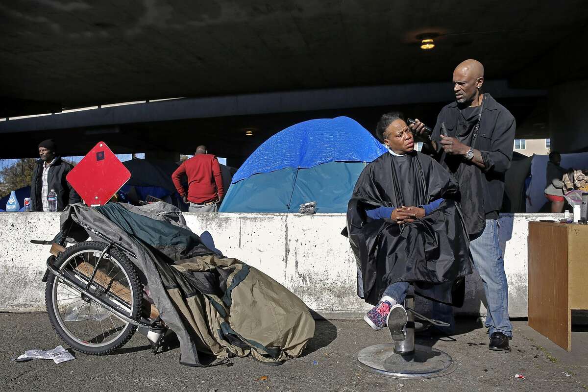 Latasha Hardman gets a haircut from her boyfriend Eugene Rumbley at Oakland's first sanctioned encampment, the "Compassionate Community" experiment, where they have been living for the past three months, under the 580 freeway at 35th and Magnolia streets in Oakland, Ca., on Thursday Jan. 26, 2017.