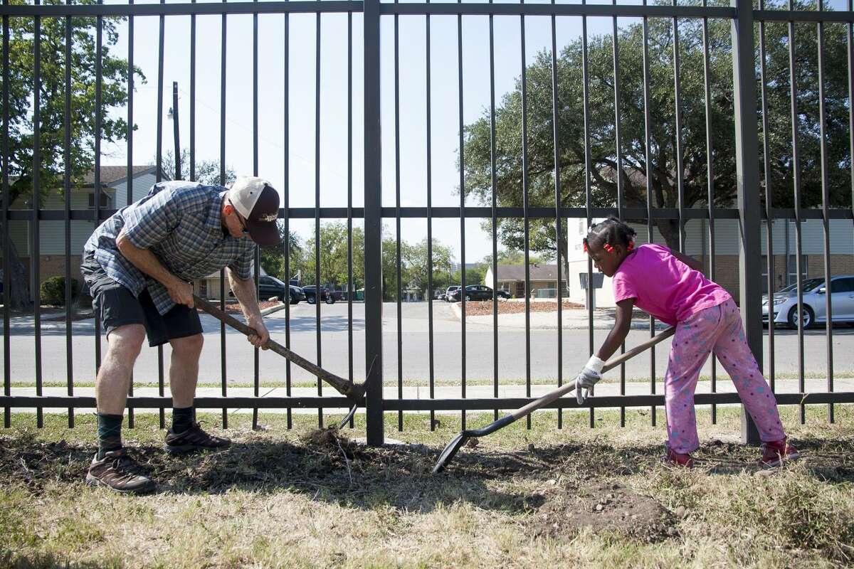 (From left) English Professor David Pryor, of the University of the Incarnate Word, works alongside Raegan Smith, 6, Friday October 24, 2014 during a youth gardening project at Ella Austin Community Center as part of their after school program.