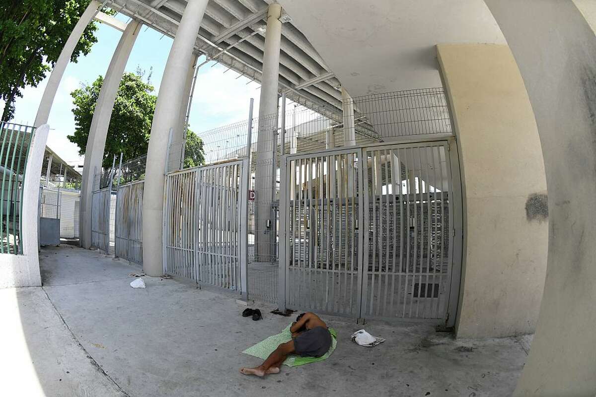 A homeless man sleeps outside the closed main gates to the world-famous Maracana Stadium in Rio de Janeiro on January 18, 2017. After playing a key role in the 2014 World Cup and 2016 Olympic Games, hosted by Brazil, the iconic Maracana Stadium has fallen into a state of abandon due to a contract dispute, and is closed to tourists. / AFP / VANDERLEI ALMEIDA (Photo credit should read VANDERLEI ALMEIDA/AFP/Getty Images)