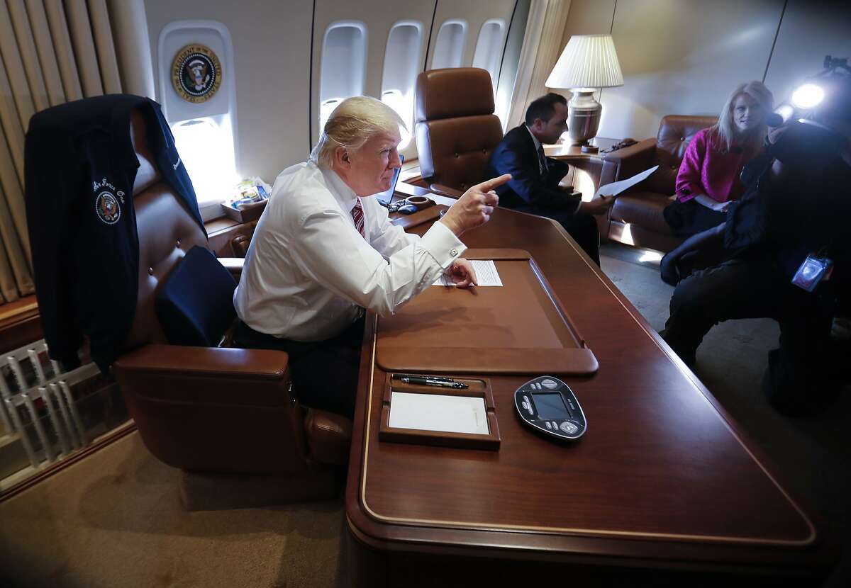 President Donald Trump points to members of the media while sitting at his desk on Air Force One upon his arrival at Andrews Air Force Base, Md.,Thursday, Jan. 26, 2017. At the center seated is Trump's Chief of Staff Reince Priebus, adviser Kellyanne Conway is at right. (AP Photo/Pablo Martinez Monsivais)