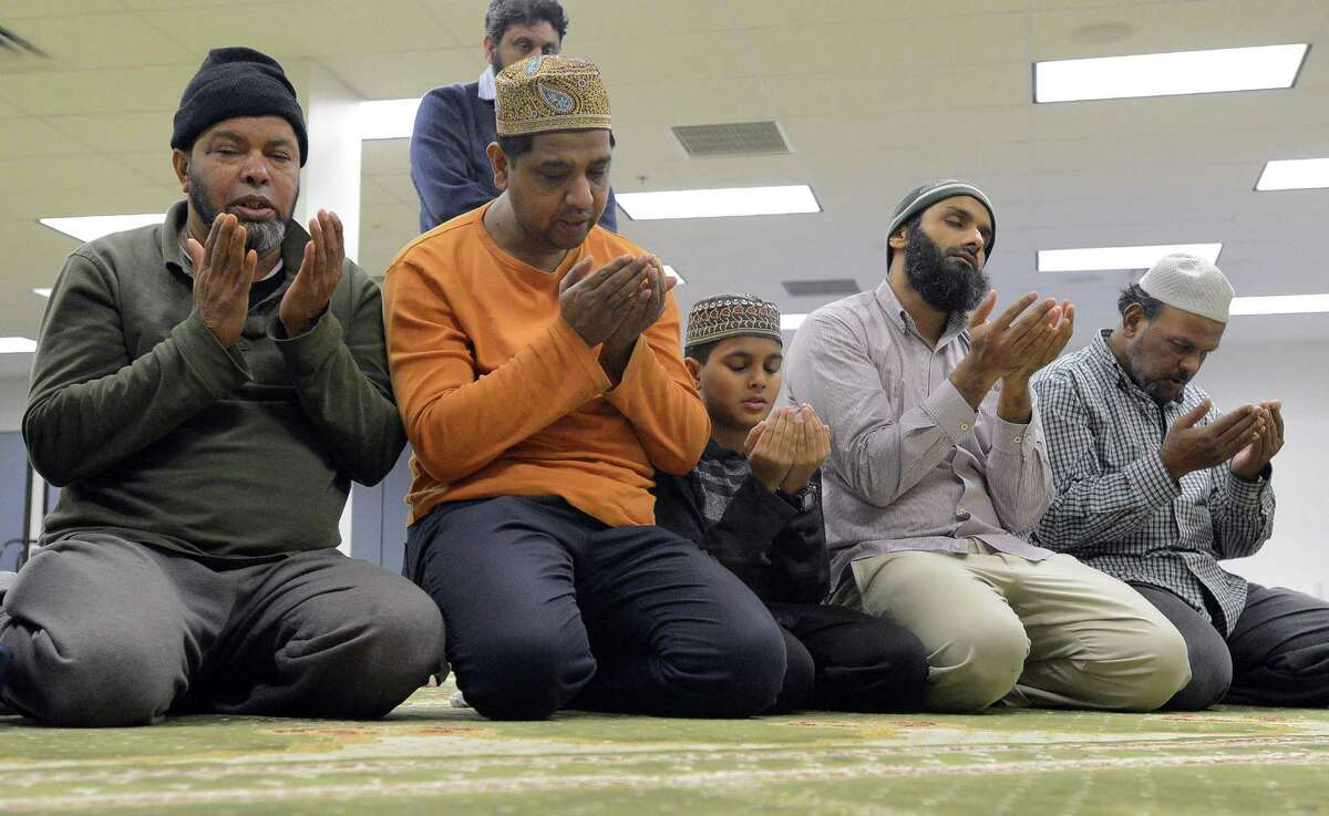 A group of men kneel before the Mehrab as they take evening prayers at the Stamford Islamic Center on Dec. 29, 2016.