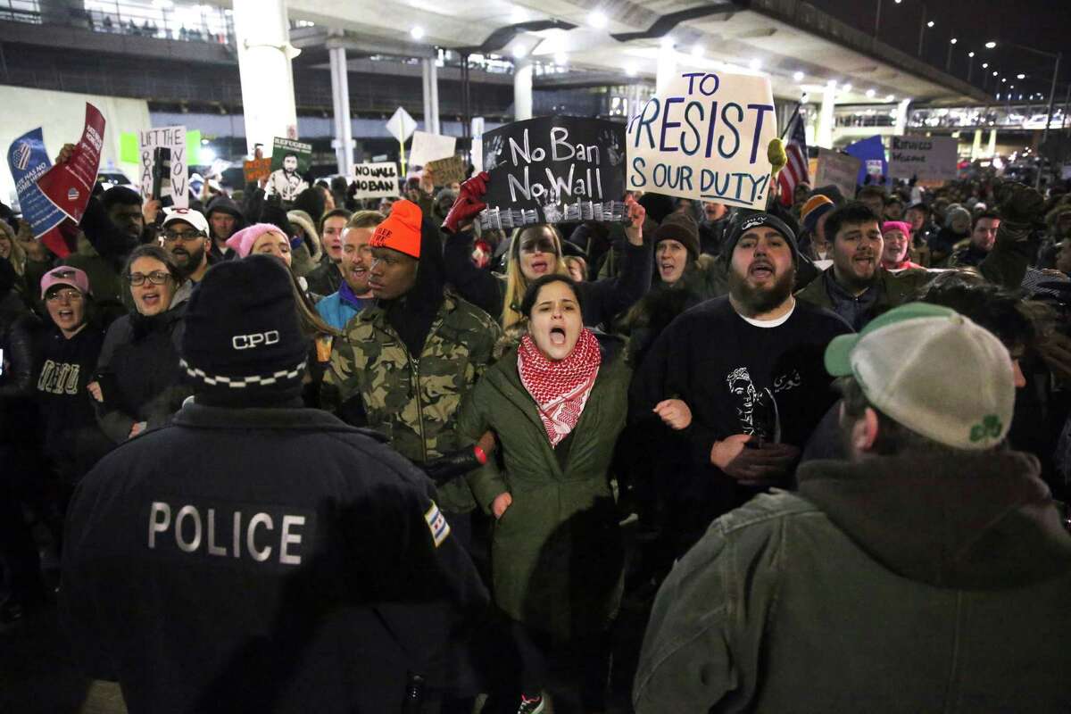 Protesters gather at O'Hare International Airport after more than a dozen people were detained, including green card holders, Saturday, Jan. 28, 2017, in Chicago. They were detained following President Donald Trump's executive order on Friday that bans legal U.S. residents and visa-holders from seven Muslim-majority nations from entering the U.S. for 90 days and puts an indefinite hold on a program resettling Syrian refugees. (Chris Sweda/Chicago Tribune via AP)
