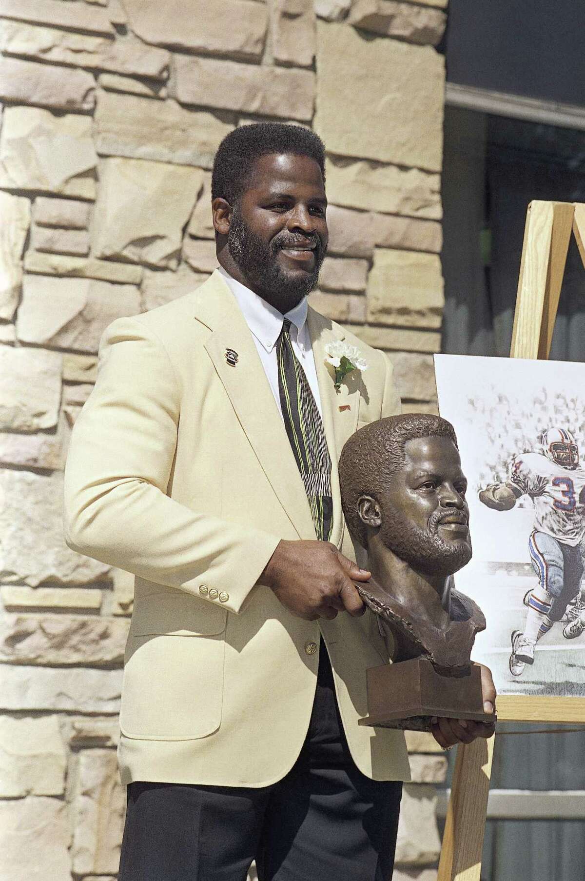 Former Houston Oilers great Earl Campbell poses with his bronzes bust after his enshrinment in the Pro Football Hall of Fame, Saturday, July 27, 1991 in Canton, Ohio. (AP Photo/Bruce Zake)