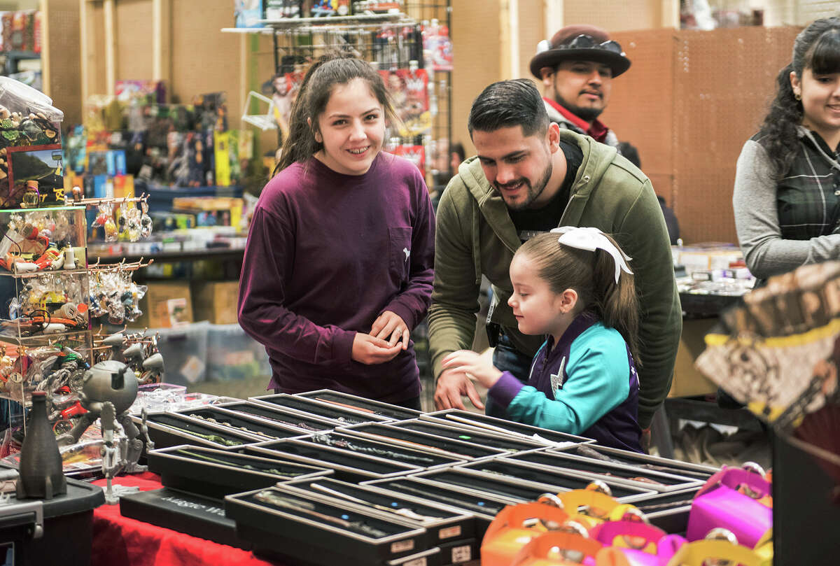 Ashley Hinojosa smiles at the camera as Ielly Hinojosa and Eddie Hinojosa browse through a selection of Harry Potter wands on Sunday, January 29, 2017 during the South Texas Collectors Expo at the Texas A&M International University Student Center.
