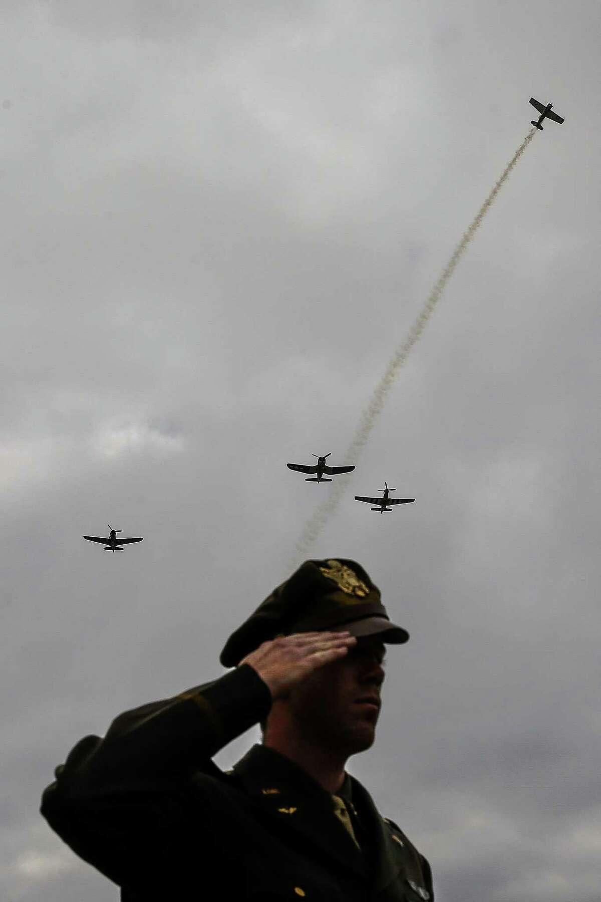 Texas Flying Legends Museum volunteer salutes as taps is played and and World War II aircraft perform a missing man formation flyover at a commemoration ceremony for the 75th Anniversary of the Pearl Harbor Attack at the George Bush Presidential Library and Museum Wednesday, Dec. 7, 2016 in College Station. President George H.W. Bush, senator Bob Dole, World War II veterans and honored guests all attended the ceremony. ( Michael Ciaglo / Houston Chronicle )