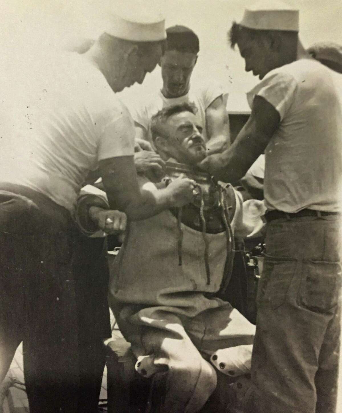 This circa 1943 photo provided by the Hartle family shows Navy diver Ken Hartle getting into his dive suit in Pearl Harbor, Hawaii. Hartle, believed to be the oldest surviving salvage diver who worked the wreckage left after the Japanese attack on Pearl Harbor in World War II, died Tuesday, Jan. 24, 2017. He was 103. (Courtesy Hartle Family via AP)