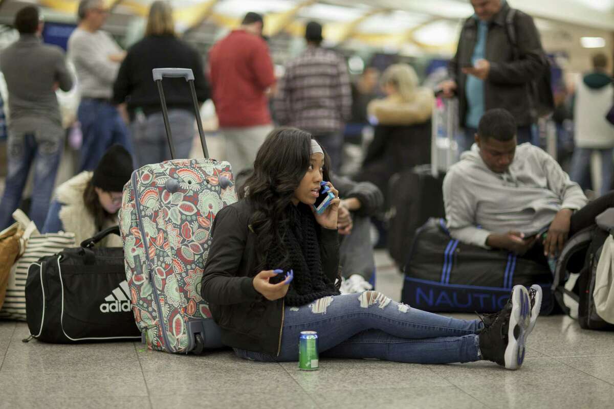A Delta passenger sits on the floor while waiting in line at Hartsfield-Jackson International Airport after Delta Air Lines grounded all domestic flights Sunday. Flight cancellations continued Monday, although Delta reported that the issue had been resolved.