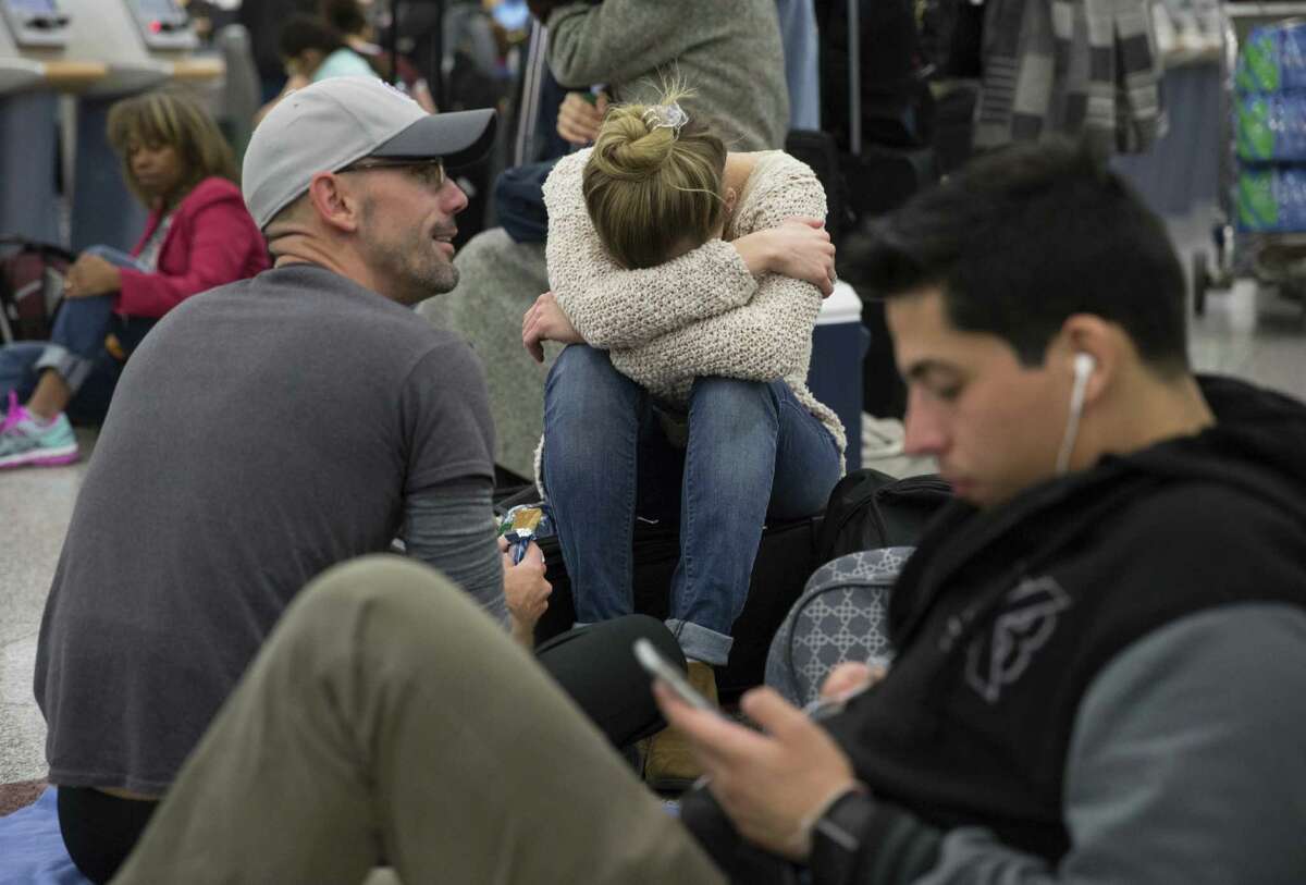 Delta passengers sits on the floor after Delta Air Lines grounded all domestic flights due to automation issues Sunday.