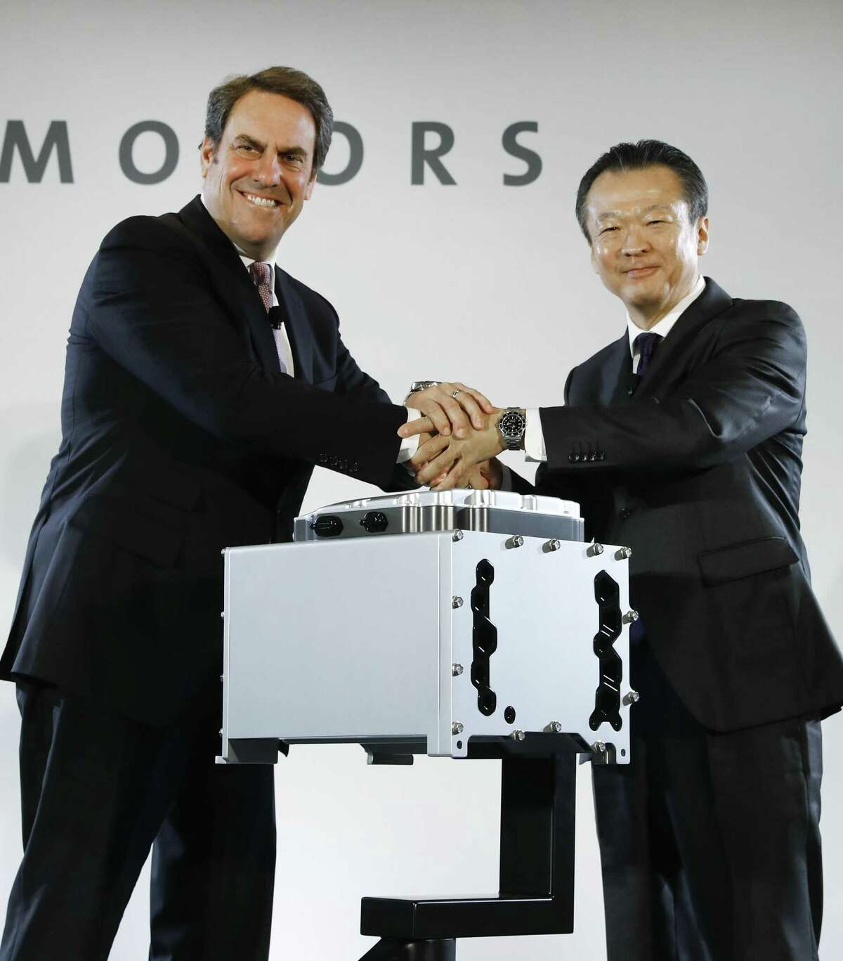 Mark Reuss (left), General Motors executive vice president of global product development, and Toshiaki Mikoshiba, chief operating officer of the North American Region for Honda Motor Co., shake hands at a news conference announcing a joint venture to produce hydrogen fuel cell systems for both companies’ vehicles.