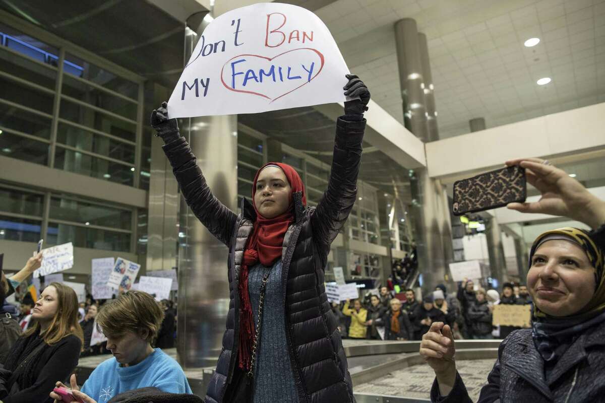 Demonstrators hold signs and chant in the baggage claim area during a protest against President Donald Trump’s executive order banning travel to the United States by citizens of several countries Sunday at Detroit Metropolitan Airport. Automakers are walking a tightrope as they court Trump, whose policies on clean-air standards, corporate taxes and trade will affect their fortunes. They have to balance that against other considerations closer to home: The traditional three U.S. automakers are based in Michigan, which backed Trump’s surprise victory but also has a substantial Middle Eastern population troubled by his executive order on immigration.