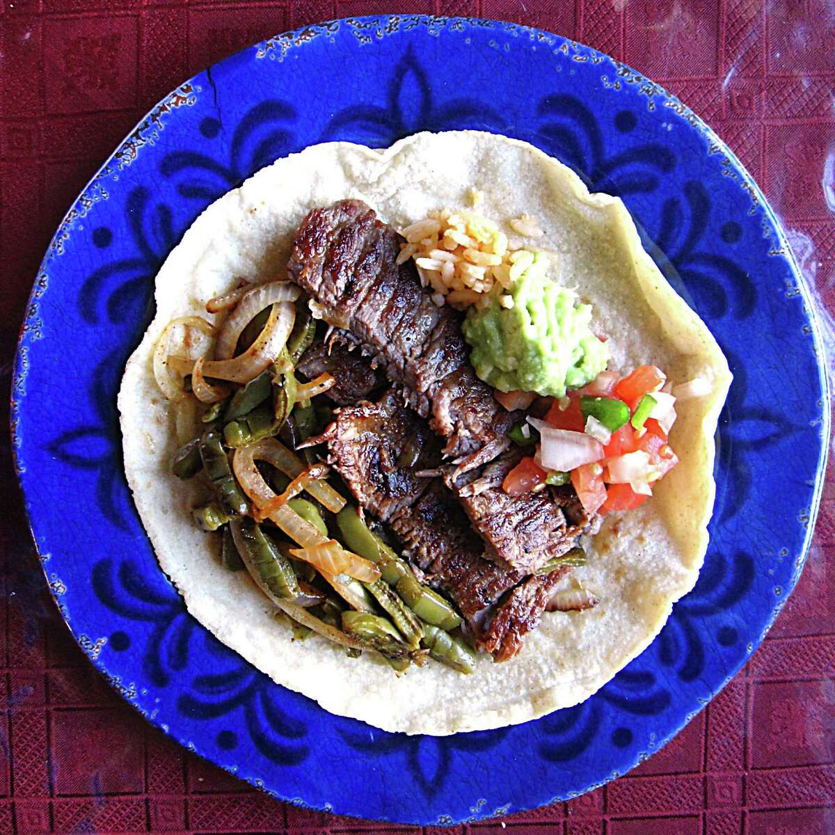 A carne asada taco on a handmade flour tortilla from Taquería Potrillo. Built from a plate that includes grilled nopales, grilled onions, pico, rice beans and guacamole.