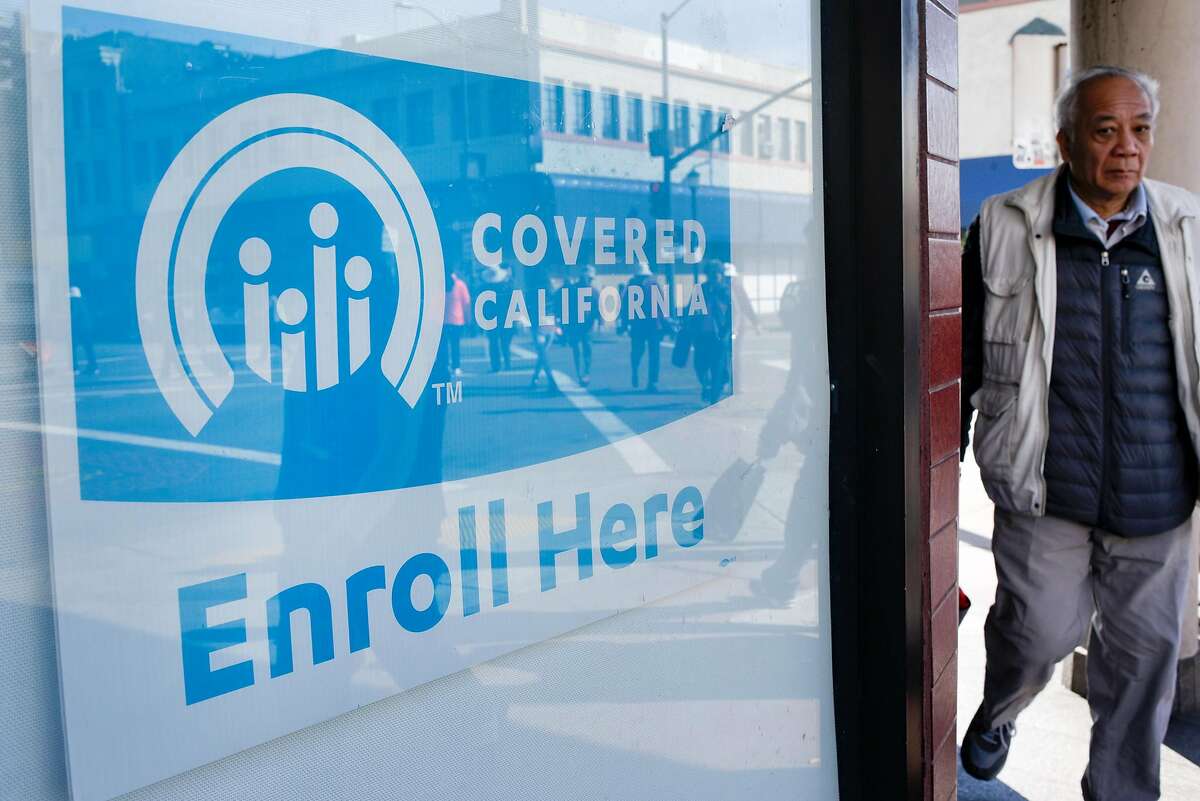 Pedestrians walk past signs for Covered California in the windows of the Asian Health Services offices on the final day of open enrollment for Covered California, the state's health insurance marketplace created by the Affordable Care Act, in Oakland, CA on Tuesday, January 31, 2017.