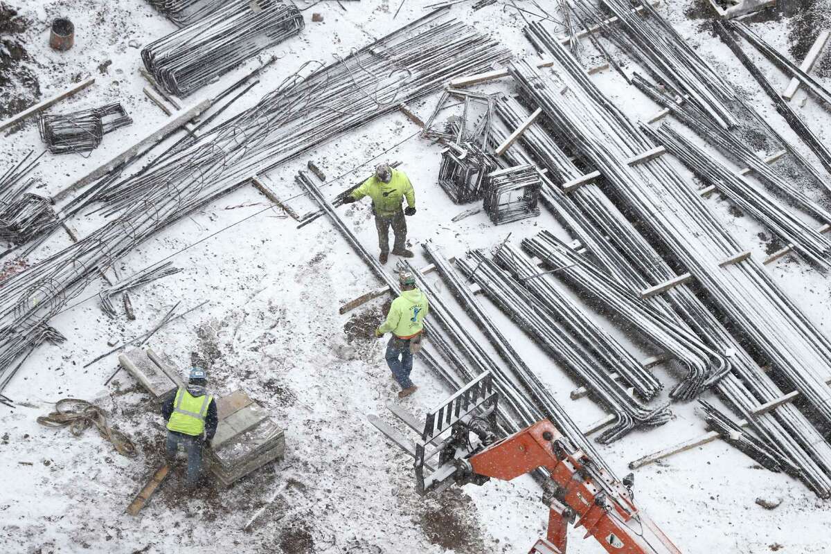 Light snow falls on construction workers, in Newark, N.J. Construction spending fell 0.2 percent in December after hitting the highest point in more than a decade in November, the Commerce Department said. The strength last month came in housing construction, which jumped 0.5 percent, with gains in single-family homes and apartments.