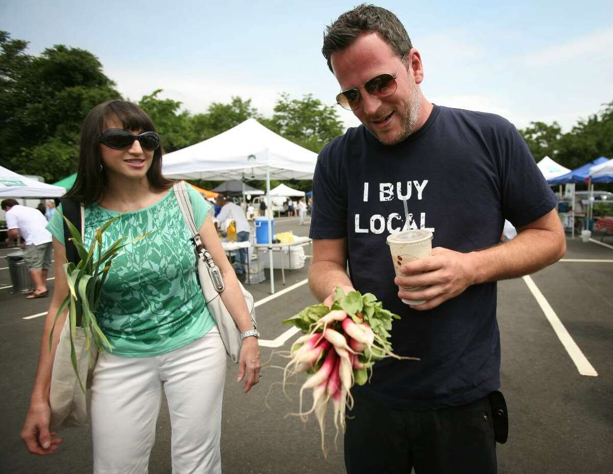 Analiese Paik, left, founder of the Fairfield Green Food Guide chats with Bill Taibe, chef/owner of Le Farm restaurant, as he shows off some breakfast radishes that he purchased at the Wesport Farmers Market.