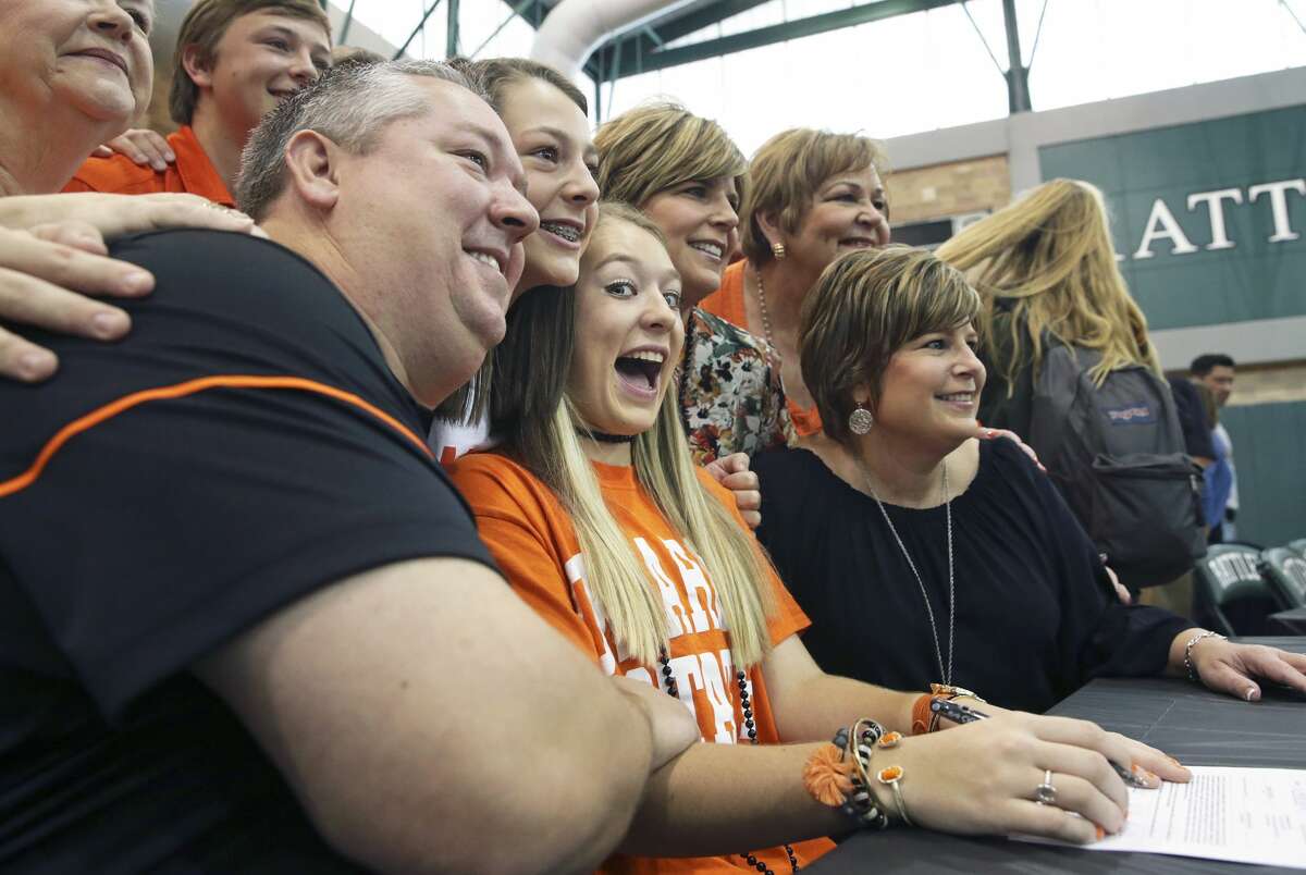 Taylor Olson feels the excitement as her family, including parents Brent and Laura, gathers around her scholarship papers as Reagan High School athletes sign scholarship papers on national signing day, February 1, 2017. Olson will play soccer at Oklahoma State.