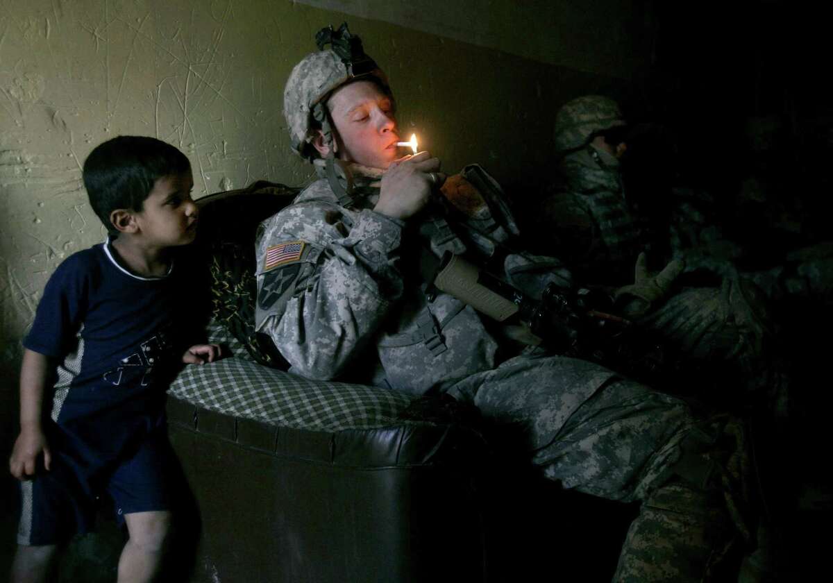 A soldier lights up a cigarette as his unit takes a rest after a foot patrol in Baghdad’s Shiite enclave of Sadr City, Iraq, in 2007. Legislation to increase the smoking age should include our young troops — to give them a chance at a healthy life.